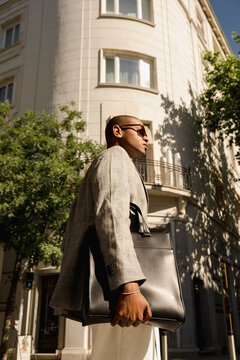 Elegant man carrying leather briefcase in street fashion editorial