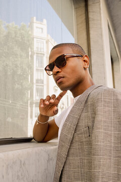 Man posing by window in street fashion editorial portrait