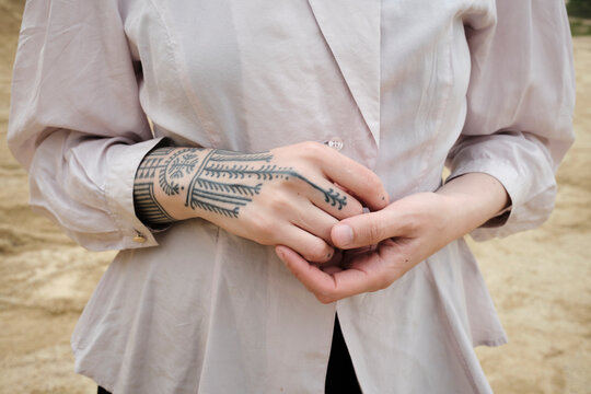 Woman stands outdoors with hands crossed in a natural setting