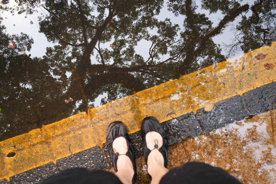 Woman standing on wet cobblestone street wearing black shoes