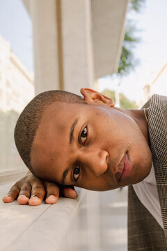 Close editorial portrait of man resting on marble ledge