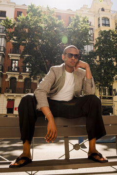 Man seated in sunlit street fashion editorial portrait