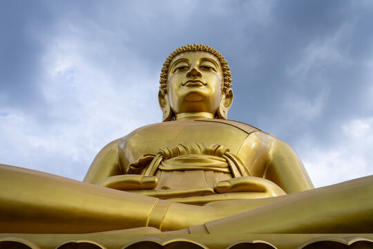 Big golden Buddha statue at a temple on a cloudy day in Bangkok