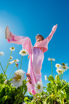 Woman balancing with raised leg among blooming daisies