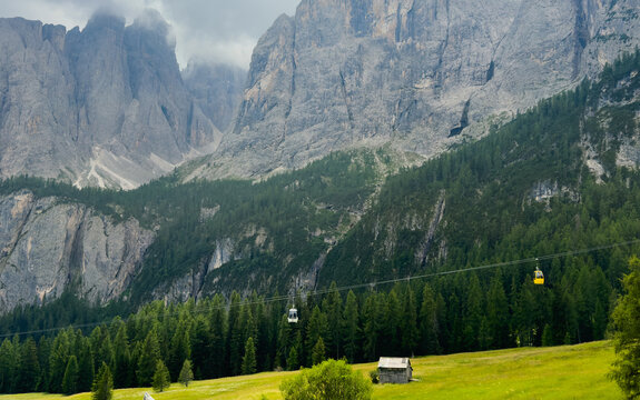 serene cable car ascending through mountainous landscape with coniferous trees and rocky terrain, ground-level perspective, green and gray tones, natural setting, travel adventure nature.