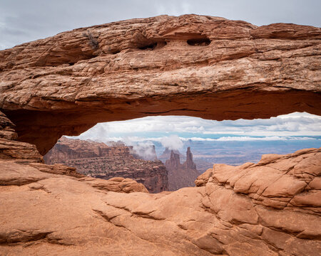 Mesa Arch Framing Canyon Spires After a Desert Storm. Mesa Arch frames the iconic canyon spires of Canyonlands National Park while lingering clouds add depth to the sweeping Utah landscape.