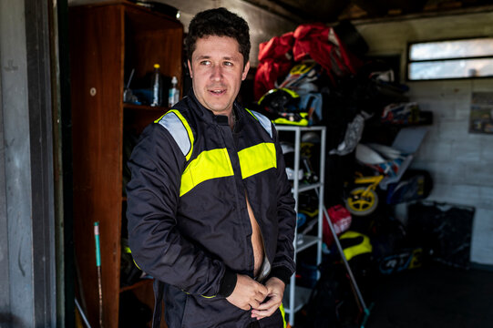 Confident kart racer in racing suit at track garage