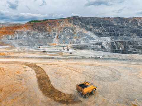 Wide open pit mine with haul truck traversing dirt road