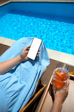 Anonymous middle-age woman with mobile phone near swimming pool.