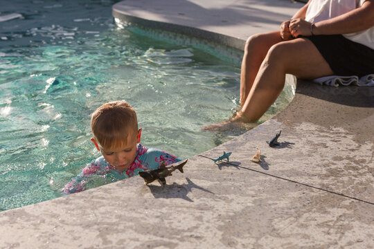 Young boy plays with toy fish and sharks in an Australian pool