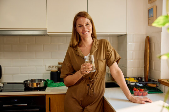 Happy woman stands in the kitchen