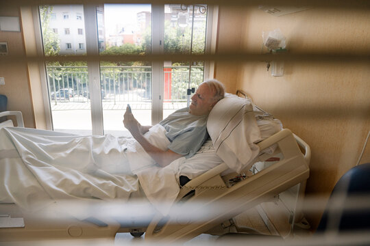 Elderly man using smartphone in hospital bed
