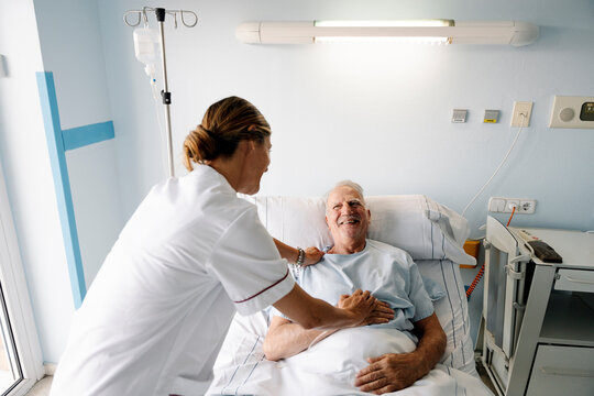 Nurse reassuring elderly patient in hospital bed