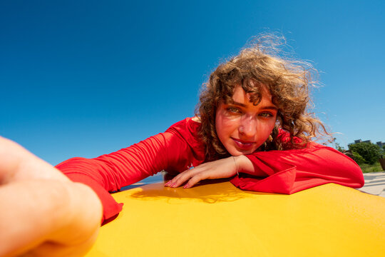 Woman in red reaching toward camera outdoors