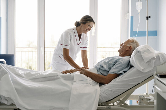 Nurse comforting elderly patient in hospital room