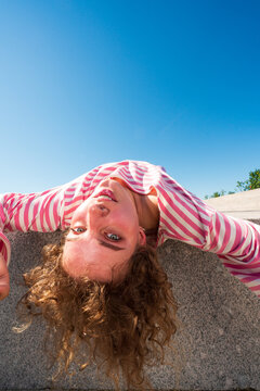 Woman leaning backward over granite slab under blue sky