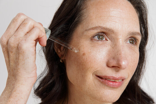 Woman Applying Skin Serum in a Bright Indoor Space