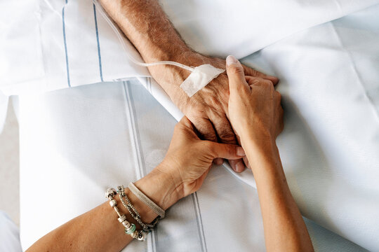 Compassionate hand holding elderly patient receiving medical care