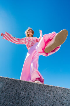 Woman in pink outfit posing against blue sky