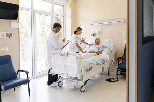 Medical team checking on senior patient in hospital bed