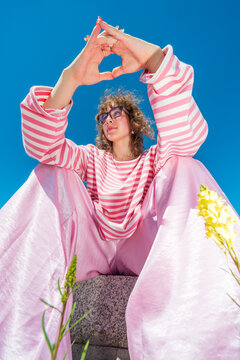 Woman in pink outfit forming shape with hands