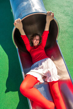 Playful Woman Relaxing on a Playground Slide