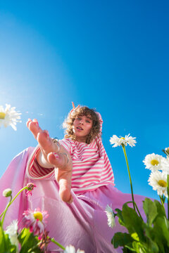 Woman in pink outfit reaching through daisies