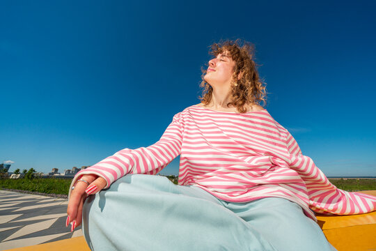Woman relaxing on yellow bench beneath blue sky