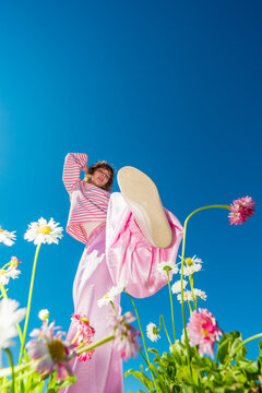 Woman raising her foot among daisies under blue sky
