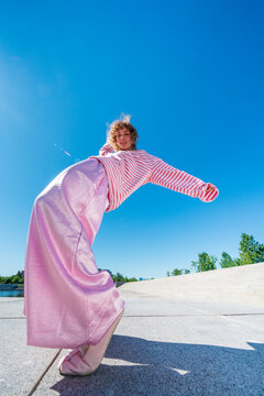 Woman in pink outfit posing under blue sky