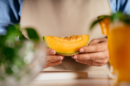 Person holding fresh cantaloupe melon slice in hands
