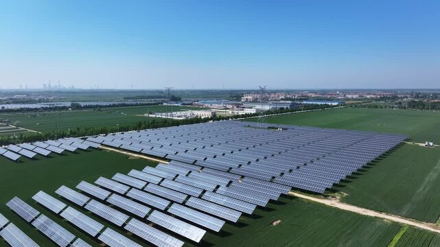 Large scale photovoltaic power station arranged in neat rows across green farmland under clear blue sky