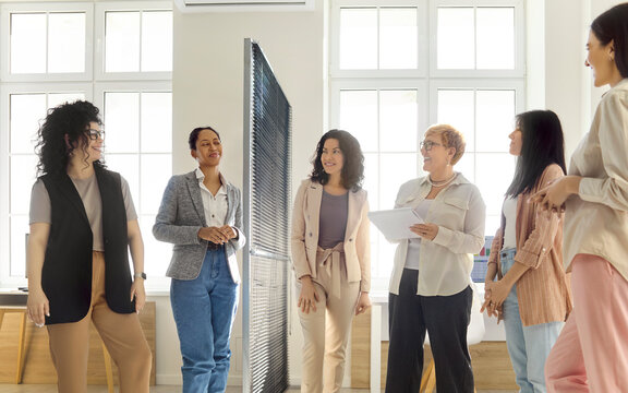 Women team meeting in office discussion. Group shares ideas during business leadership seminar, building teamwork and training skills in a bright workspace. Teamwork and leadership theme clear.