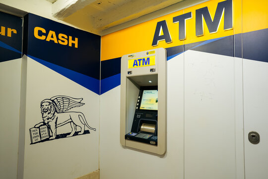 Venice, Italy - May 19, 2026: ATM machine mounted on wall with blue and yellow branding, featuring a lion graphic and cash withdrawal instructions visible