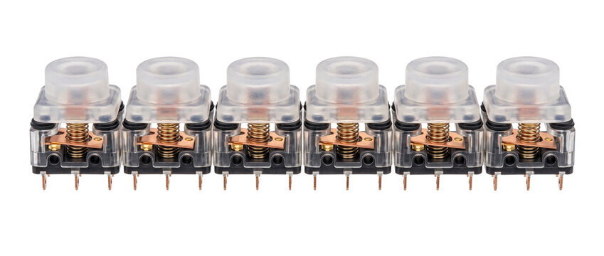 Tactile micro switches electronic components lined up in a row on a black background, featuring transparent housings, internal copper coil springs, and metal terminals for industrial hardware designs.