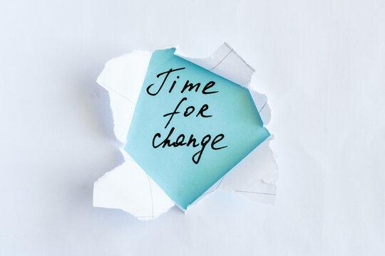 Time for Change Concept with Handwritten Message Revealed Through Torn Paper on Blue Background