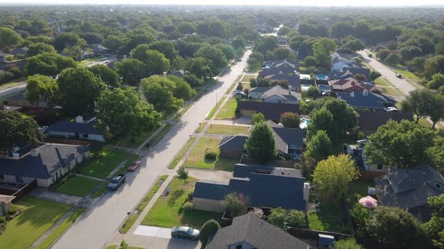 Curving roadway intersections connect single family parcels across suburbs DFW. Pitch dark rooftops, private corner lots, parked vehicles highlight community living, Coppell, Texas
