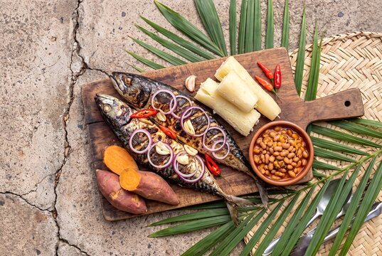 Traditional Angolan Mufete with Grilled Mackerel Cassava Sweet Potato and Beans on a Wooden Board