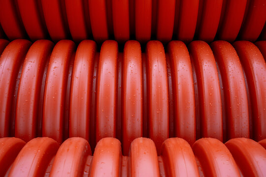 Close-up of wet red corrugated plastic pipes