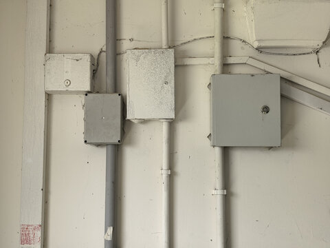 Electrical junction boxes and utility pipes on white wall interior