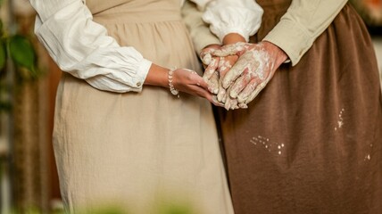Hands covered in clay, a couple working together in a pottery studio