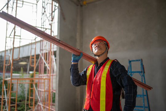 Construction Worker Carrying Steel Beam at Building Site