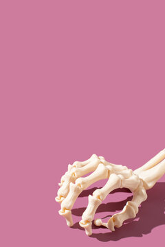 Skeleton hand on bright purple background for a spooky and festive halloween holiday. Vertical with copy.