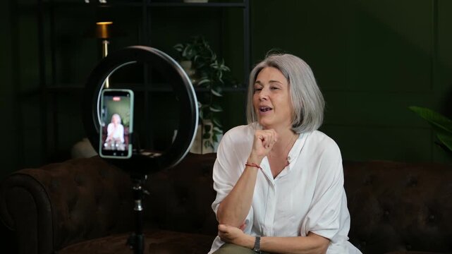 Senior woman creating content for her social media channel using a smartphone and ring light