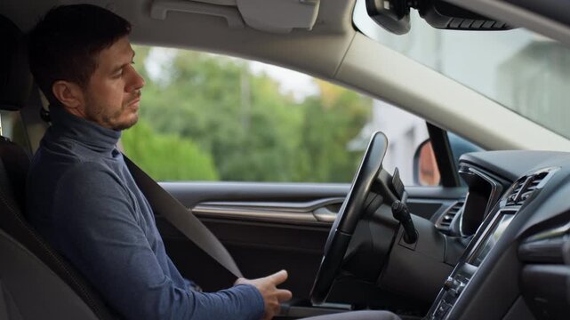 Man getting into car and fastening seat belt before driving