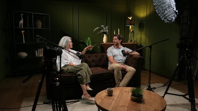 Man and woman having a conversation while recording a podcast in a professional studio setup