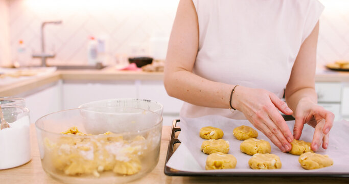 Baking process. Cookies preparation. Woman chef hand shaping peanut round dough pieces placing on culinary sheet with parchment paper.