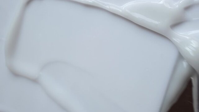 Thick white cosmetic cream being smoothed with spatula creating beautiful and satisfying texture