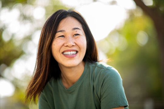 Japanese woman smiling outdoors in natural sunlight