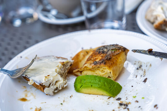 Breakfast plate with toasted bread, cream cheese, avocado slice and a folded omelet